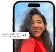 iPhone 15 displaying a Voiceover announcement describing a photograph as: a person with wavy black hair laughing